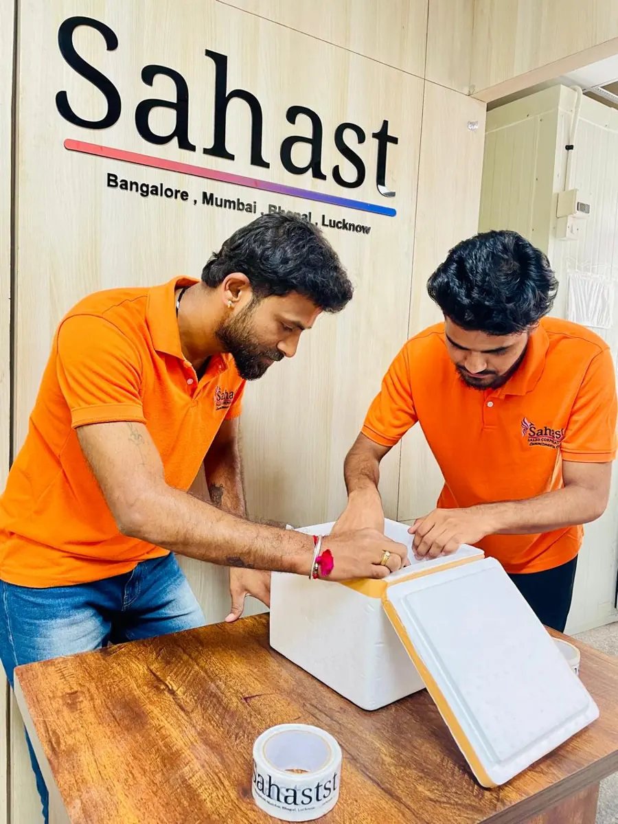 Two team members packing medicines into an insulated cold-chain box